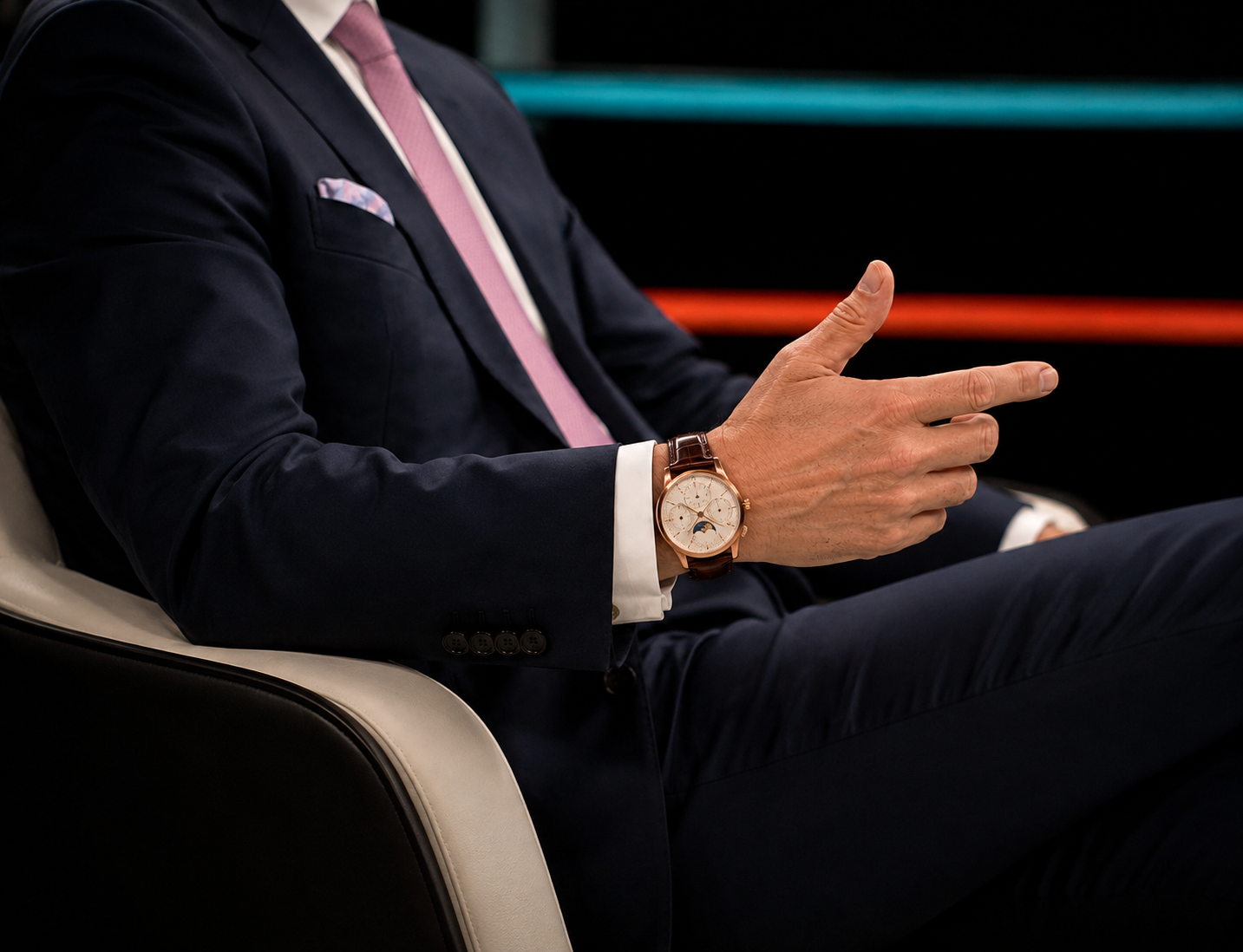 Mann im dunkelblauen Anzug mit mechanischer Uhr in Roségold-Optik am Handgelenk