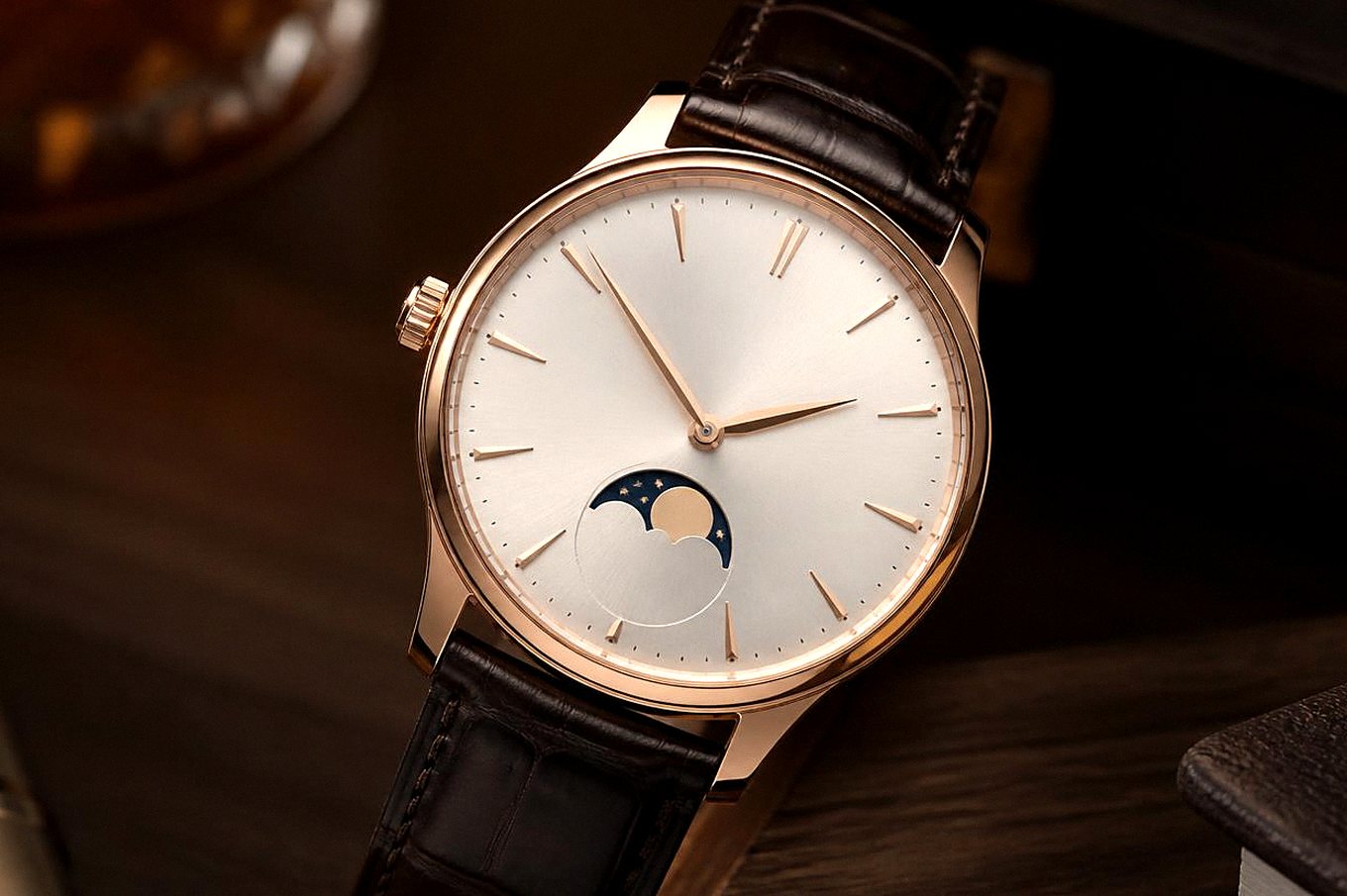 Mechanische Uhr in Roségold-Optik mit silberweißem Zifferblatt und braunem Lederarmband auf einem Holztisch